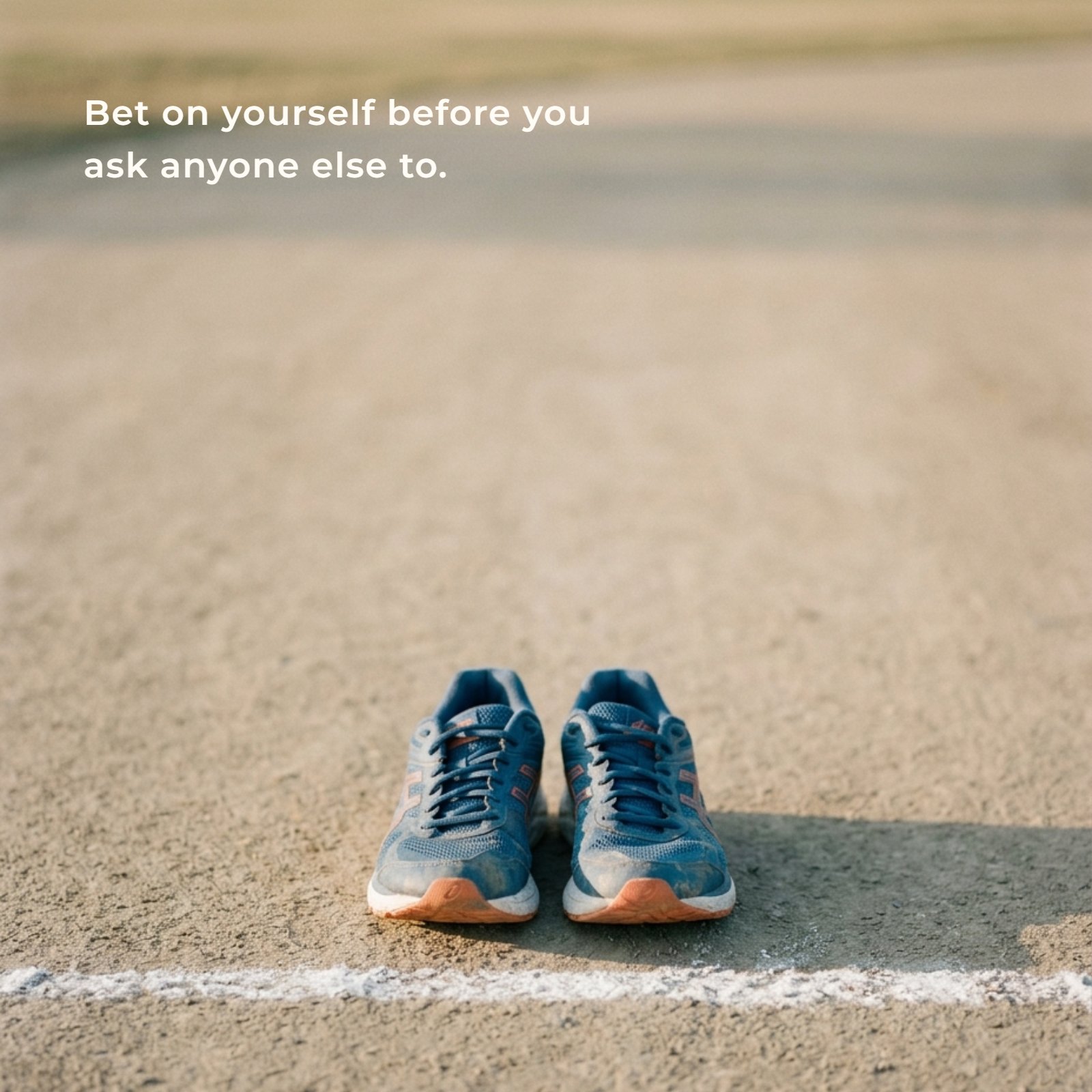Minimalist 1:1 photograph featuring a single pair of running shoes positioned behind a white chalk starting line on plain neutral ground in soft warm light, representing the quote: Bet on yourself before you ask anyone else to.
