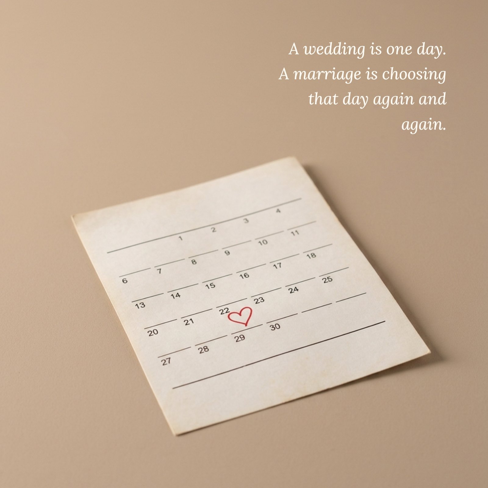 Minimalist photo of a single calendar page with a small red heart hand-drawn on one date, with the quote text "A wedding is one day. A marriage is choosing that day again and again." over the clean area of the image.