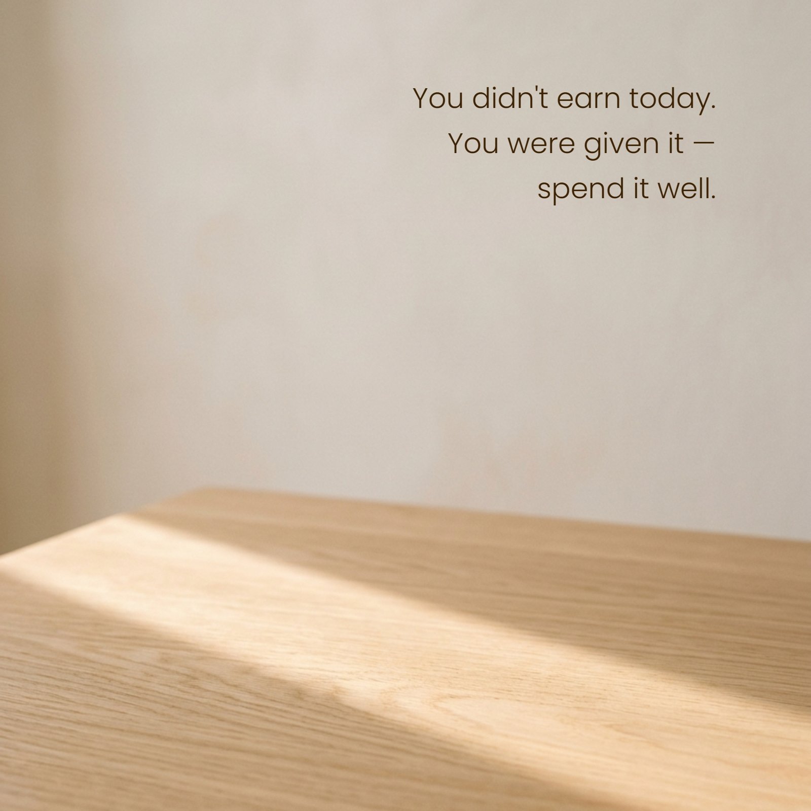Minimalist 1:1 photograph showing warm morning light on a wooden table surface. The text 'You didn't earn today. You were given it — spend it well.' is written over the background.