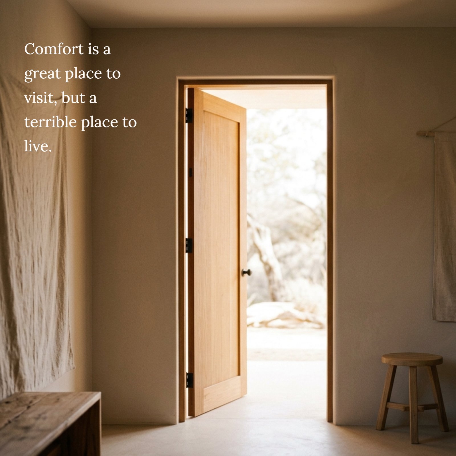 A 1:1 minimalist photograph of a single wooden door open to bright daylight, with soft warm light coming from a cozy neutral-toned room. The text overlay reads: “Comfort is a great place to visit, but a terrible place to live.”