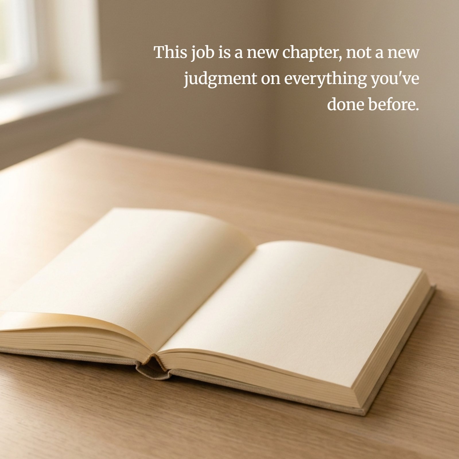 An open, empty book resting on a wooden desk bathed in soft daylight, overlaid with the motivational quote: This job is a new chapter, not a new judgment on everything you've done before.