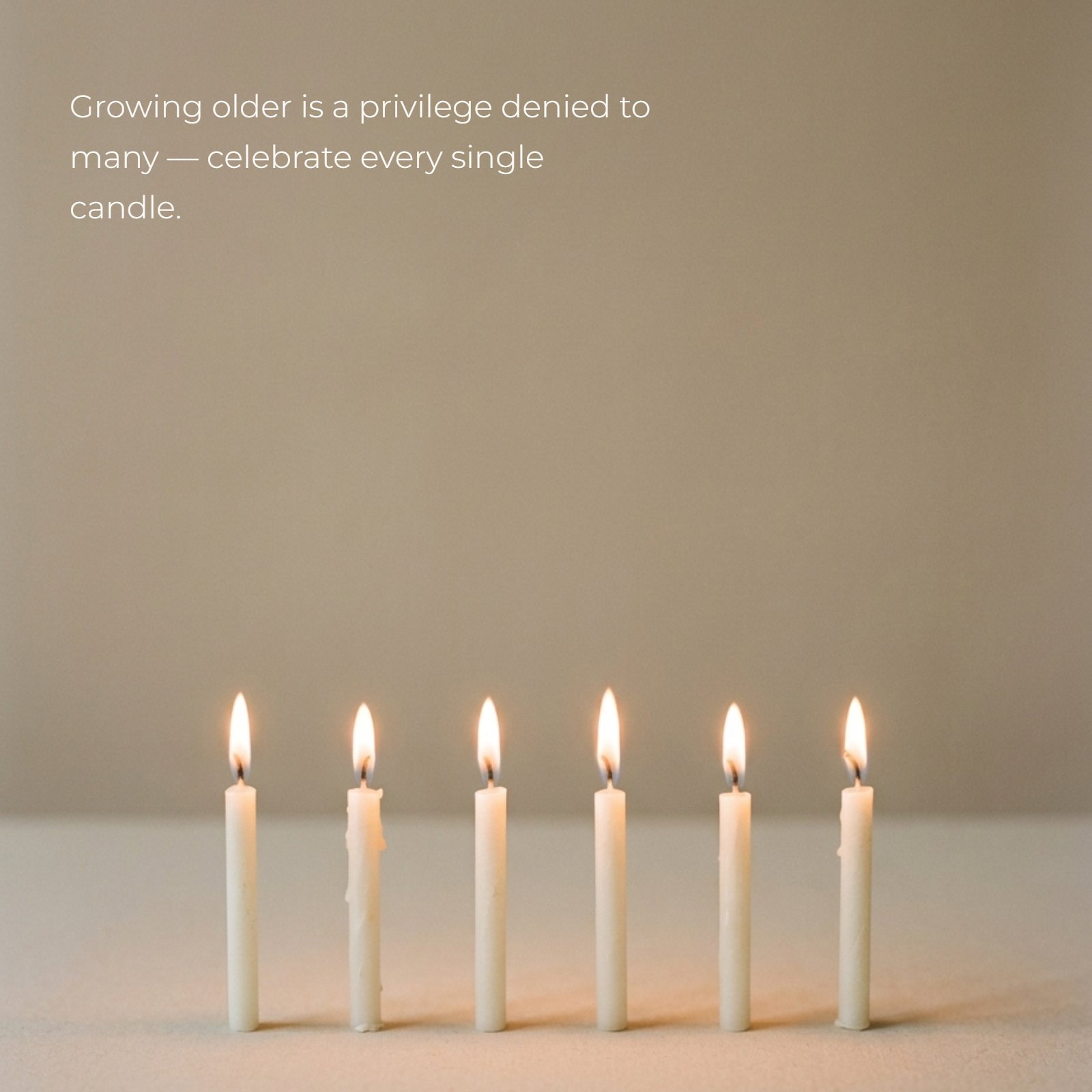 A minimalist photo of a row of small, lit white candles with warm, glowing flames on a plain neutral surface and background, featuring the superimposed quote "Growing older is a privilege denied to many — celebrate every single candle."
