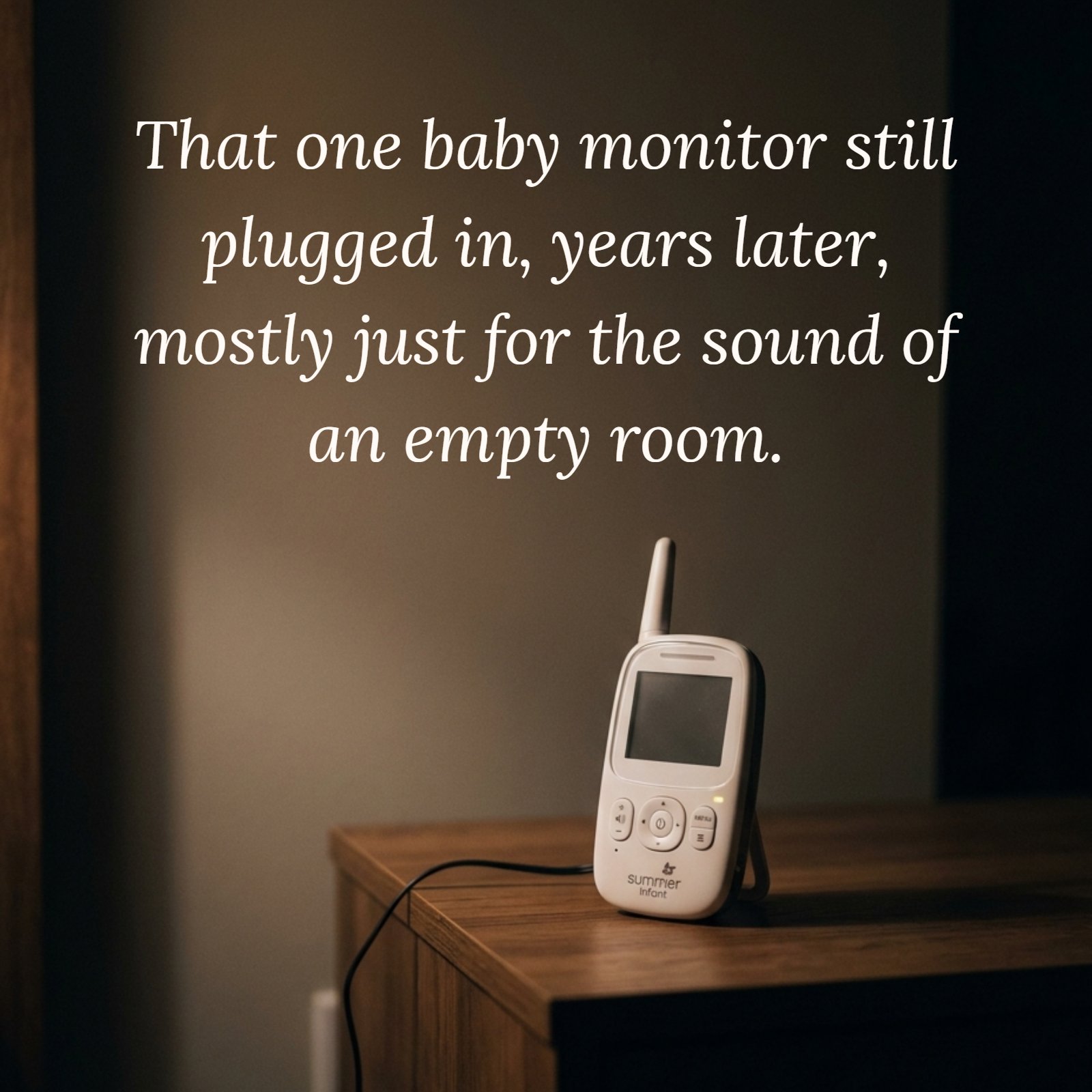 A minimalist photo of a single baby monitor resting on a wooden nightstand in a dimly lit room at night. Large blank wall space is visible above it.