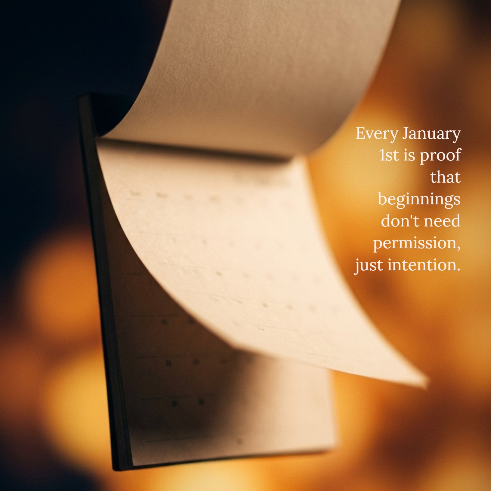 An image featuring a minimalist, textured calendar page mid-flip against a warm amber and soft bokeh background. Dark midnight blue shadows frame the scene. Overlaying the image is the quote, "Every January 1st is proof that beginnings don't need permission, just intention."