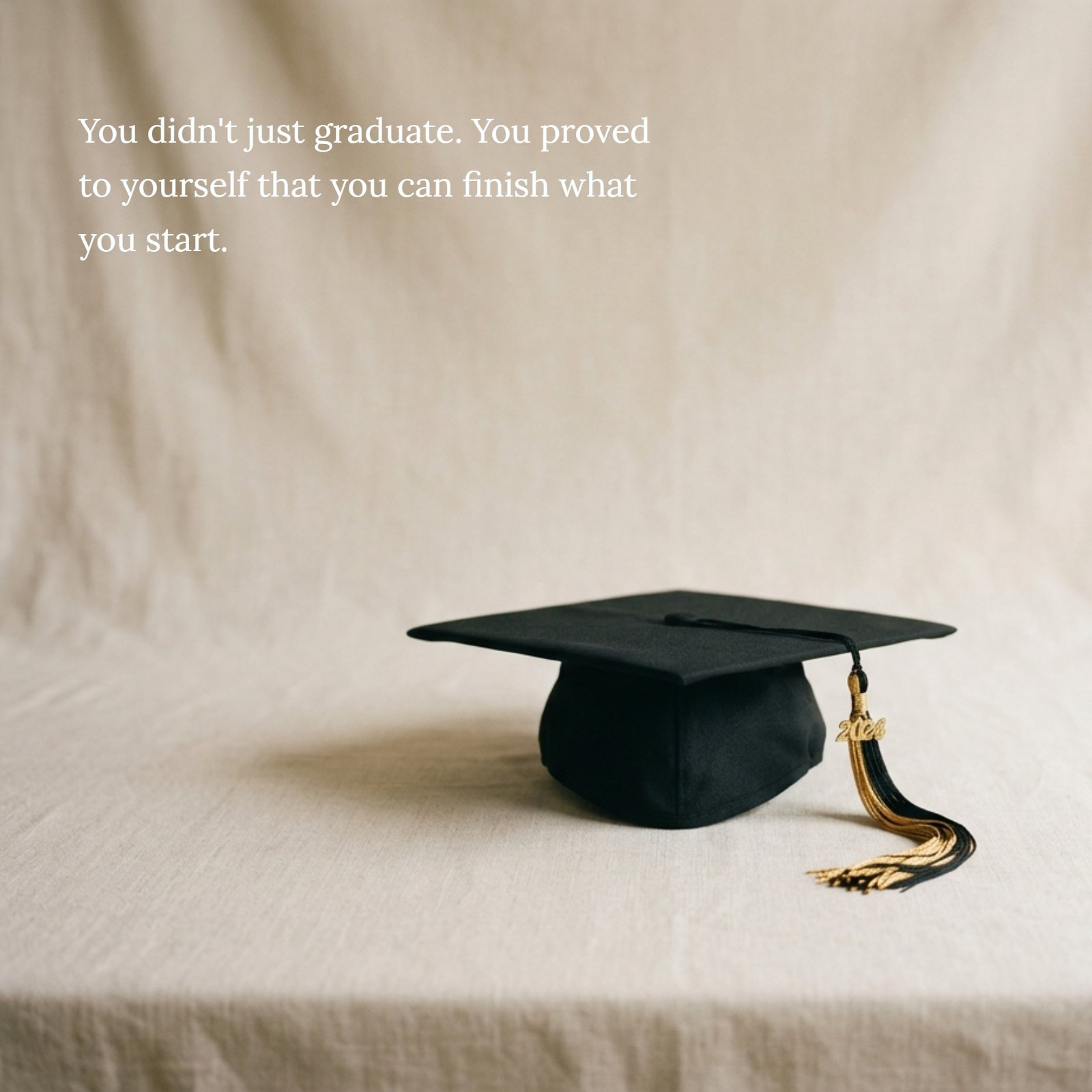 A vertical minimalist photograph of a single black graduation cap with a gold tassel resting on a textured, plain neutral beige surface, with soft warm light. The image provides clean negative space above the cap, ideal for overlaying the quote: "You didn't just graduate. You proved to yourself that you can finish what you start."