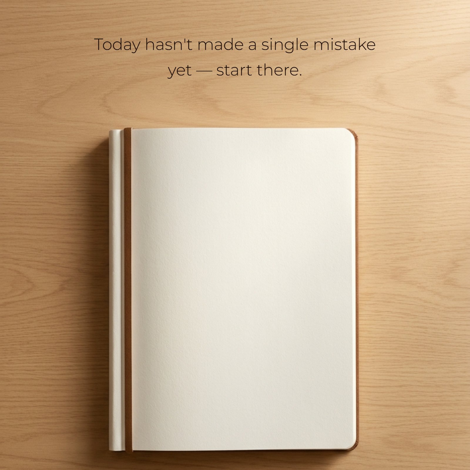 A minimalist photo of a blank open notebook page on a light wood desk, illuminated by soft morning light, with the text 'Today hasn't made a single mistake yet — start there.' centered on the page.