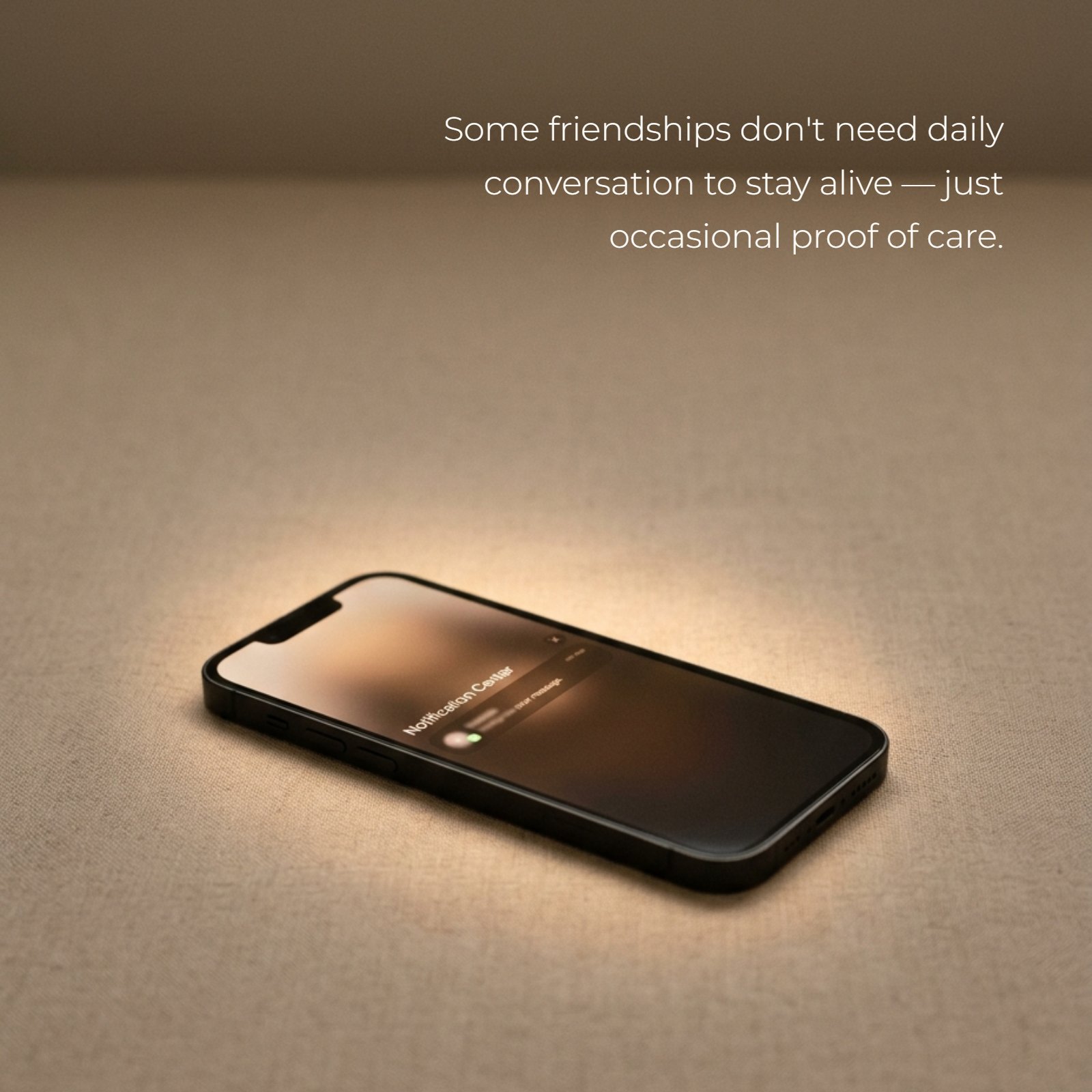 Minimalist image of a smartphone on a warm-lit, plain surface with a soft glow on the screen. The text overlays the Friends quote: "Some friendships don't need daily conversation to stay alive — just occasional proof of care."