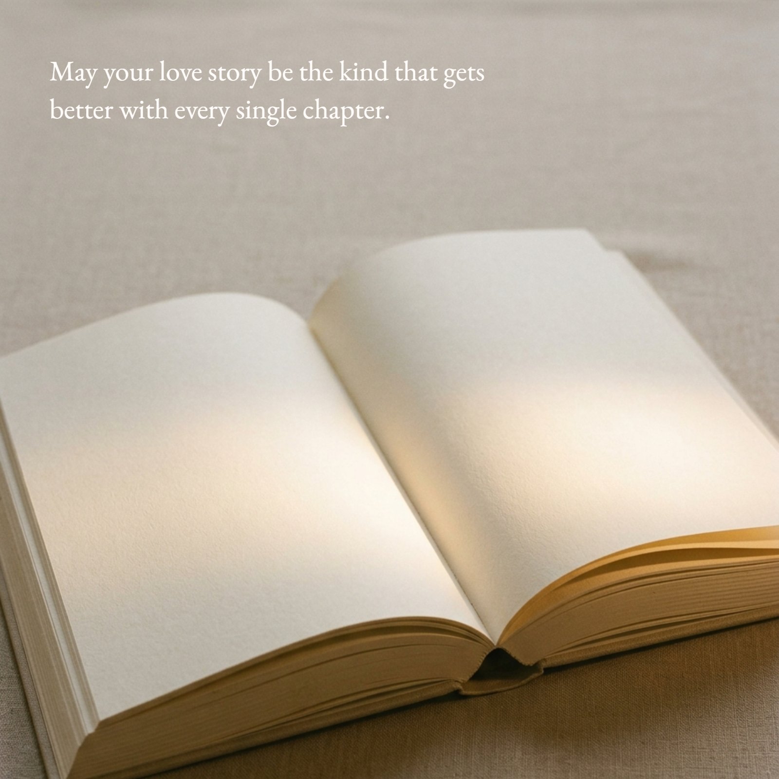 An open book with soft, warm light spilling across blank pages. The quote 'May your love story be the kind that gets better with every single chapter' is written on the left page in a vintage font.