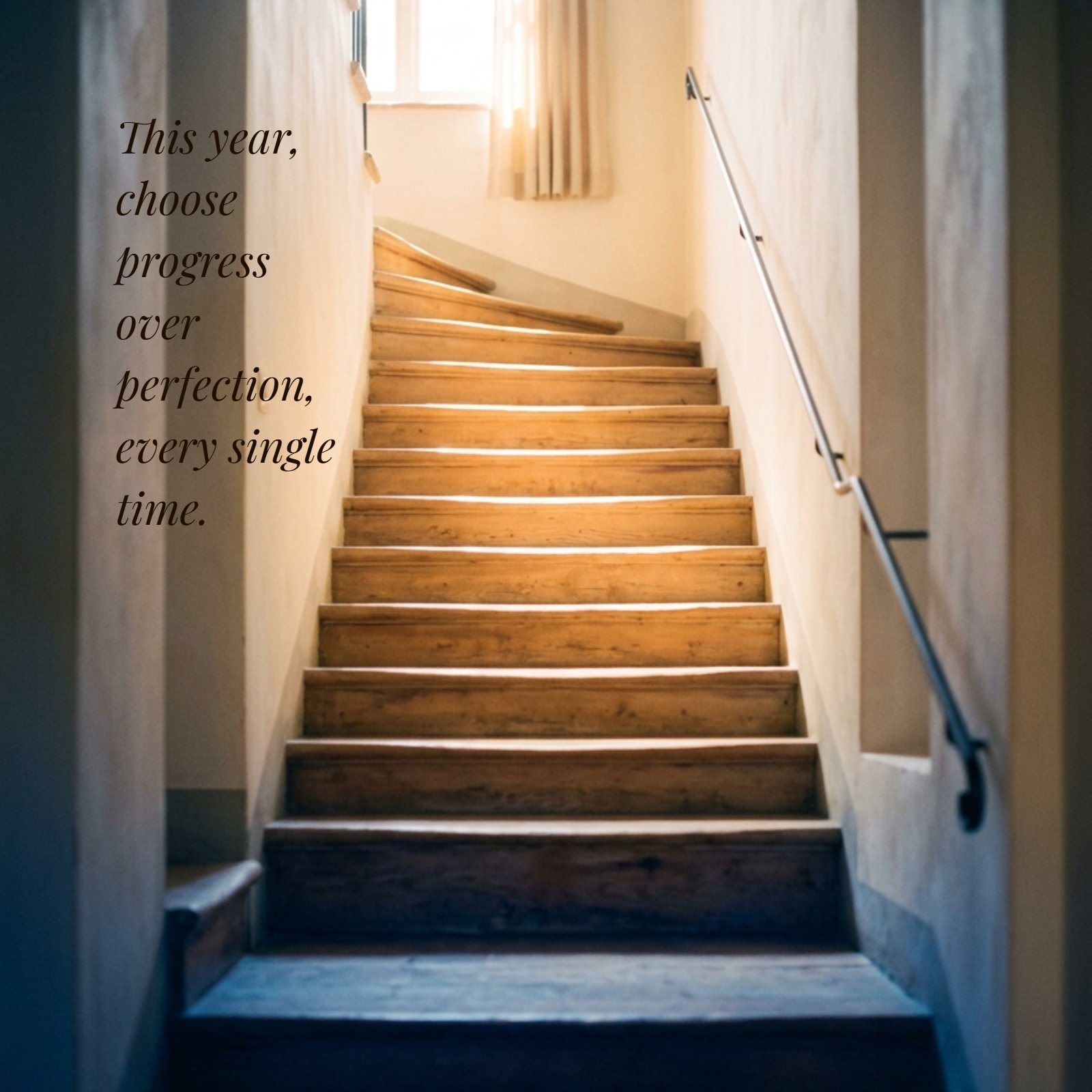 Soft-focus photo of a staircase bathed in warm golden light from above, with deep blue shadows at the base. The quote, 'This year, choose progress over perfection, every single time.', is overlaid in a gentle, warm-toned serif font.
