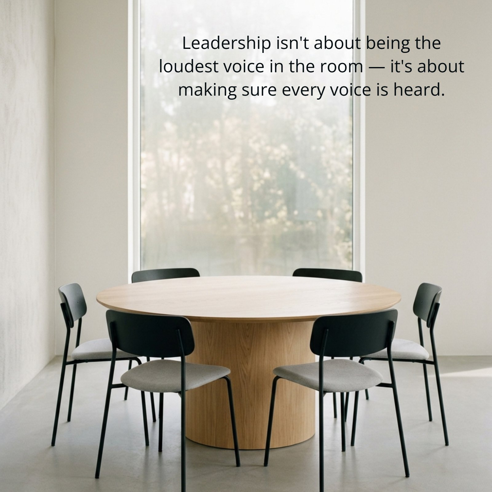 A minimalist photo of an empty round wooden conference table and six empty chairs by a large window with the quote Leadership isn't about being the loudest voice in the room — it's about making sure every voice is heard.
