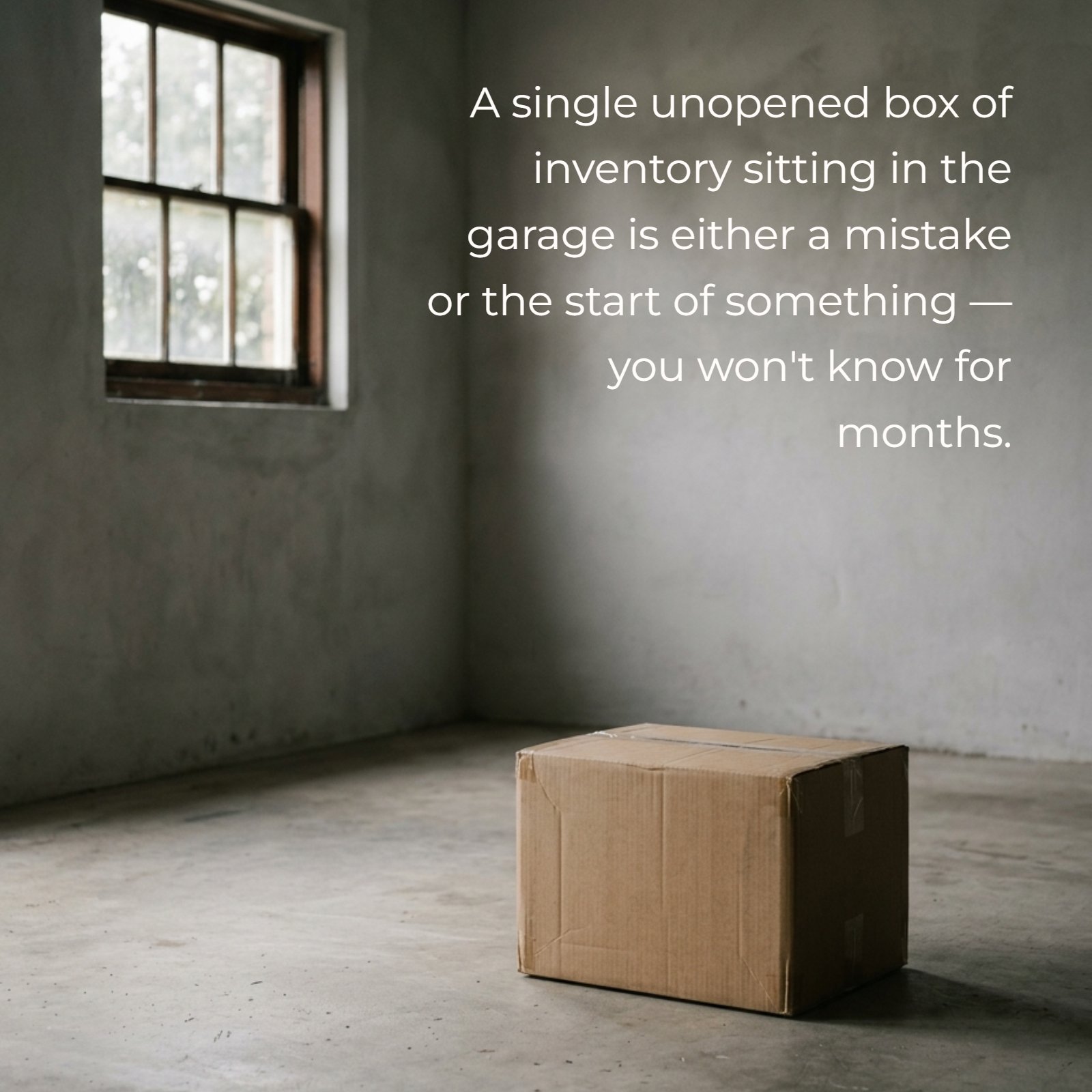 A lone cardboard box rests on a concrete floor in a dimly lit, austere room with a single window.
