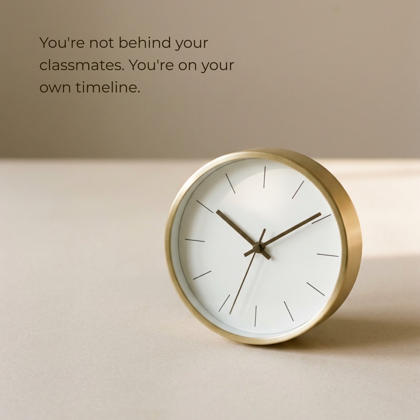 Minimalist photo of a gold clock on a beige surface with soft warm light. Overlaid text says 'You're not behind your classmates. You're on your own timeline.'