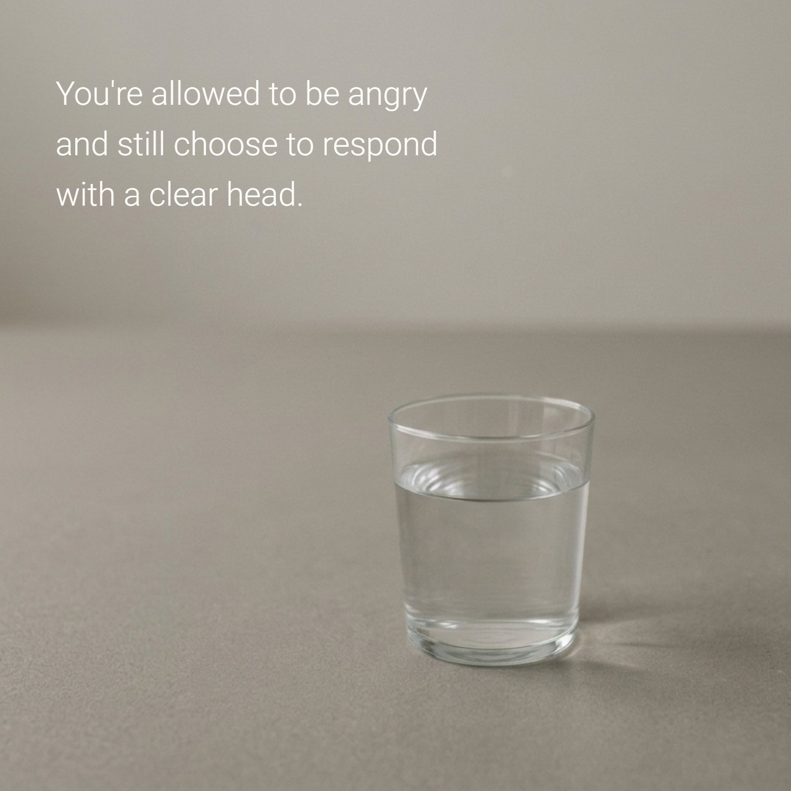 A minimalist image with a clear head wisdom quote: "You're allowed to be angry and still choose to respond with a clear head," featuring a single glass of still water on a neutral surface.