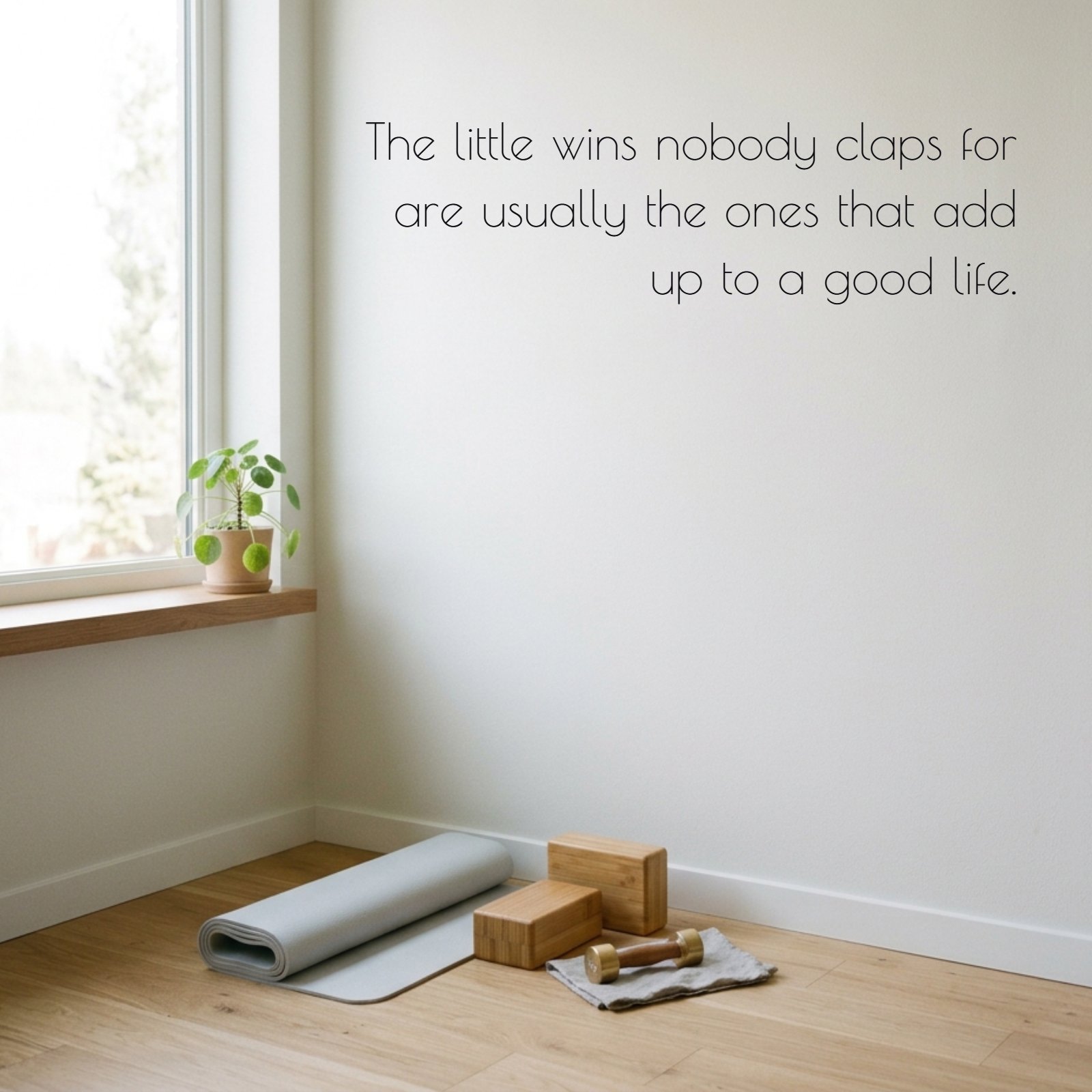 Minimalist bright home gym corner with soft morning light, a folded yoga mat, and a large clean pale wall featuring the happiness quote: "The little wins nobody claps for are usually the ones that add up to a good life."