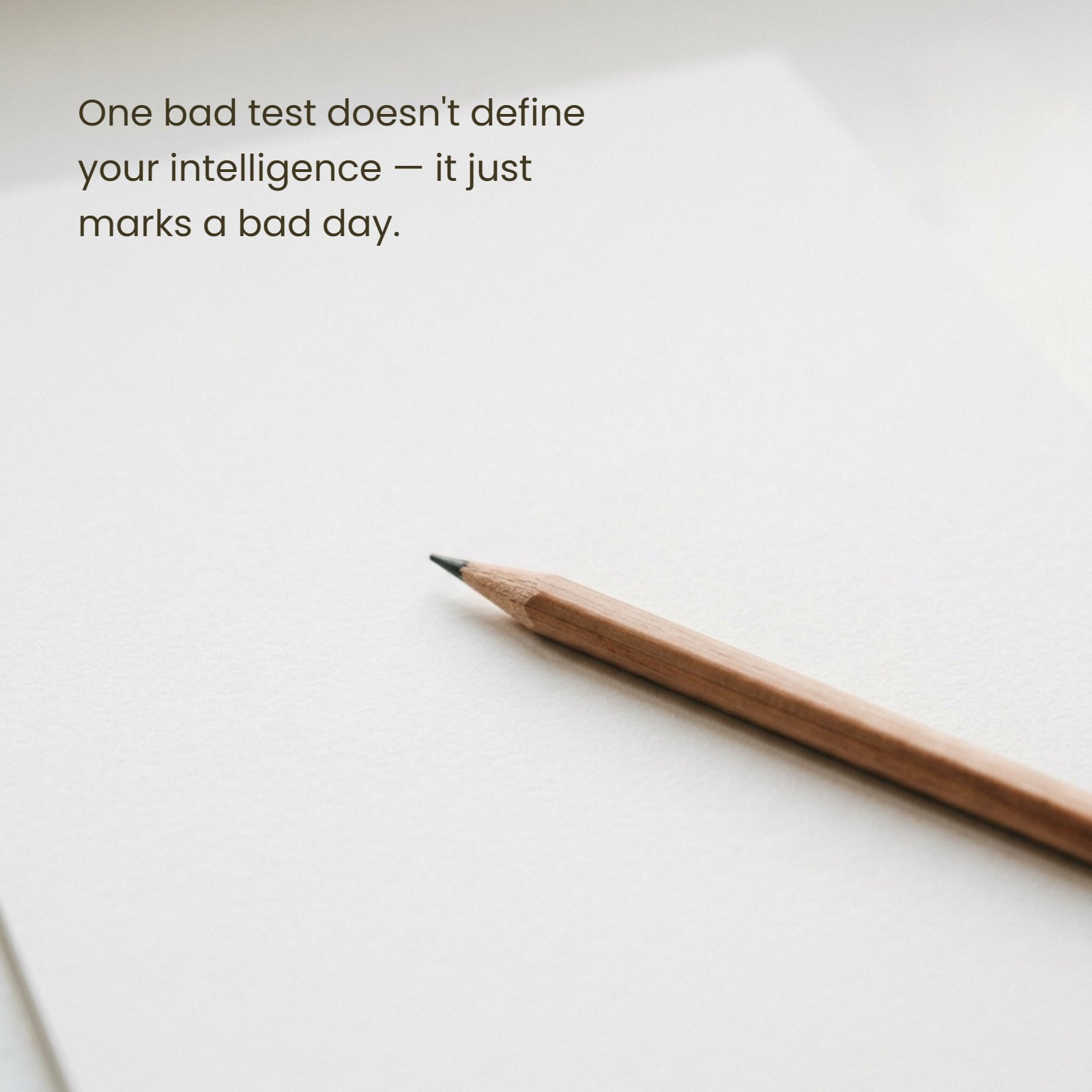 A pencil rests on a textured white paper sheet with the inspirational quote, "One bad test doesn't define your intelligence — it just marks a bad day."