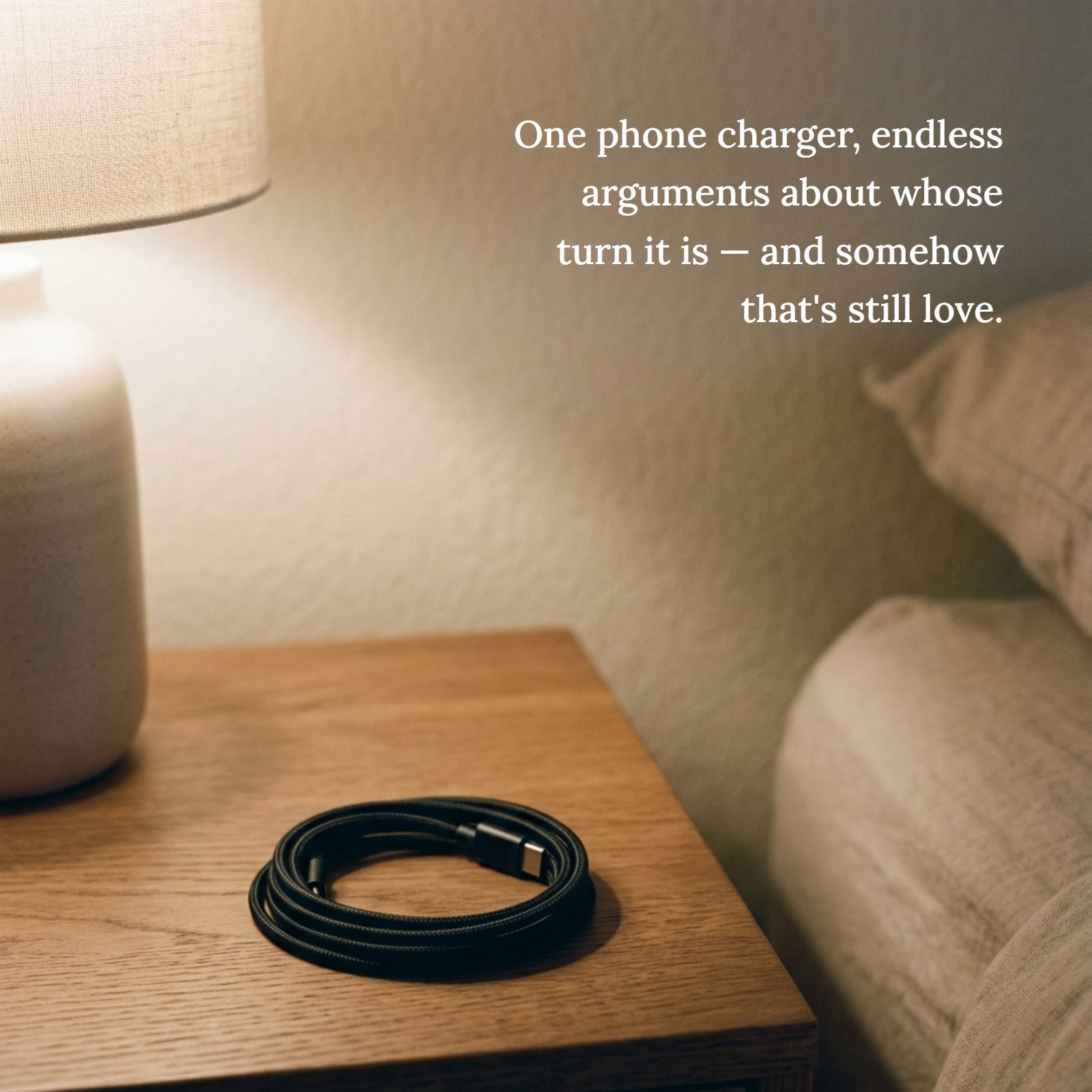 Minimalist photo of a black coiled phone charger on a bedside table under warm light, illustrating the quote about couples arguing over whose turn it is.