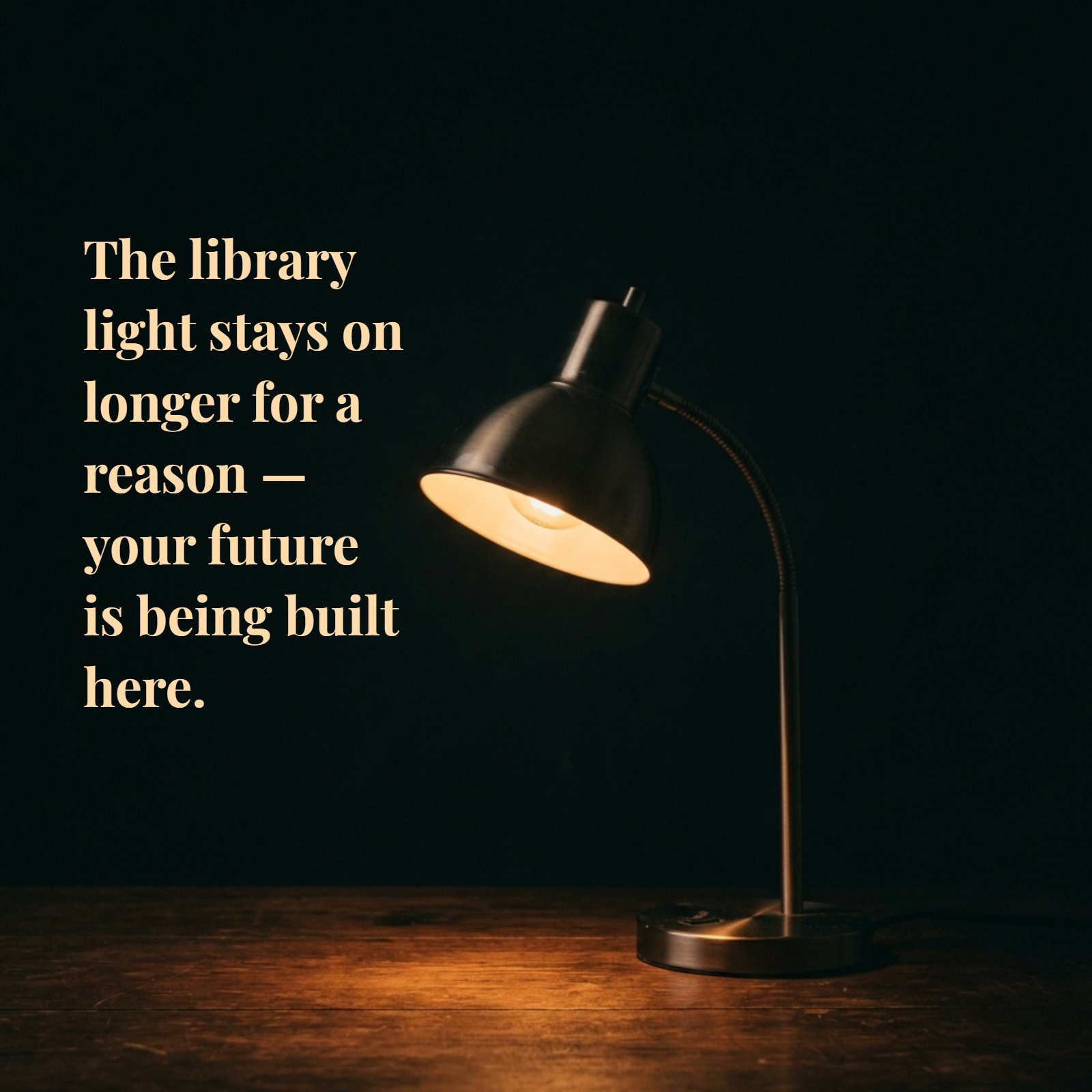 A minimalist photo of a single, metal goose-neck desk lamp glowing softly with warm light on a dark wooden desk against a plain black background, featuring the superimposed white quote: The library light stays on longer for a reason — your future is being built here.